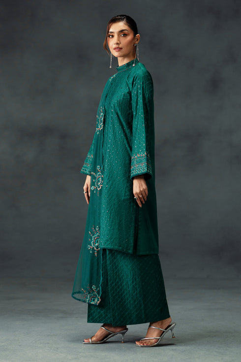 Woman wearing a green embroidered outfit against a gray background